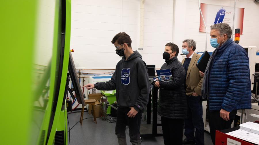 UW-Stout plastics engineering major Jared Pavlis demonstrates for Missy Hughes, WEDC secretary and CEO, how to make an injection molded part for a catheter. Looking on are Menomonie Mayor Randy Knaack, third from left, and Randy Hulke, executive director of UW-Stout’s Discovery Center.