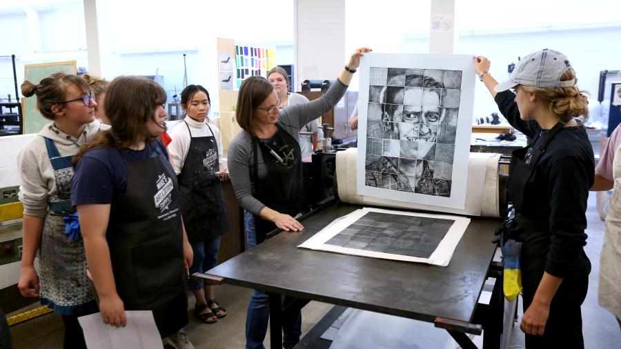 Rachel Bruya, design department, holding print on the left, teaches a printmaking class. Bruya has been promoted to associate professor with tenure.