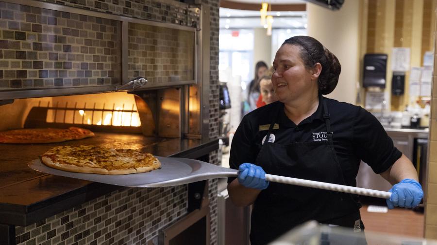 A Dining Services worker makes a pizza in the student center.