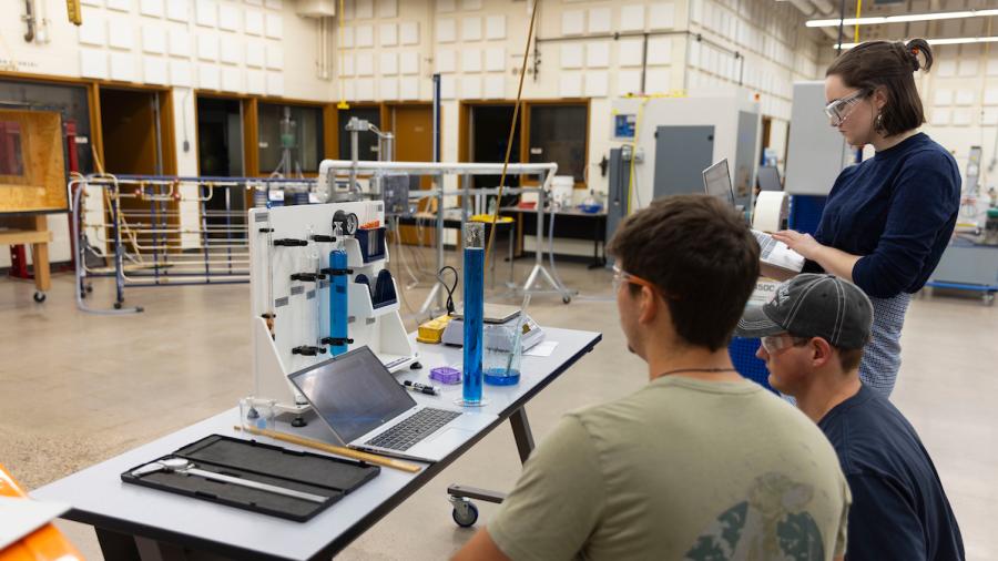 Students experimenting at a fluid properties apparatus station in an engineering lab