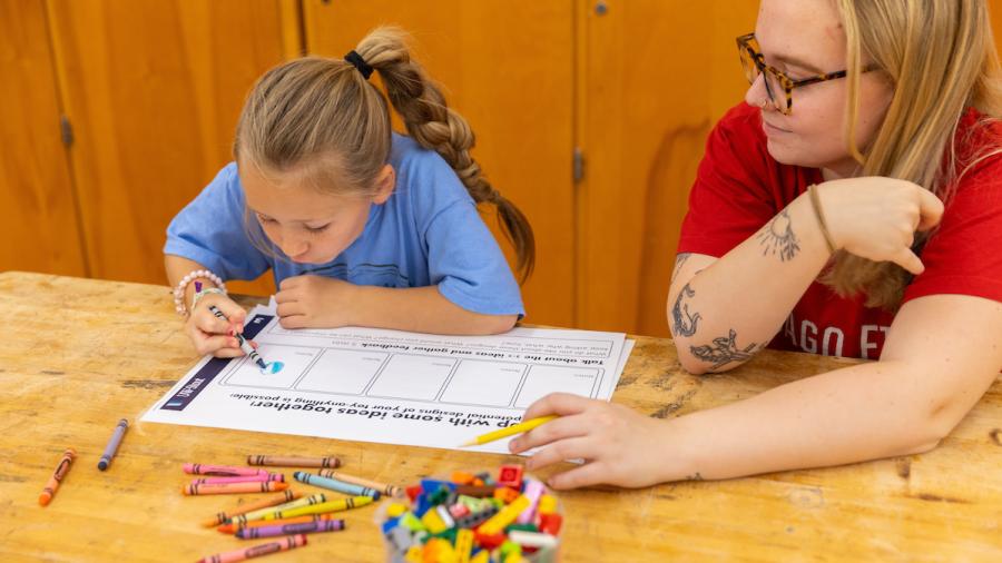 A Design for Industry student and first-grader draw a toy design.