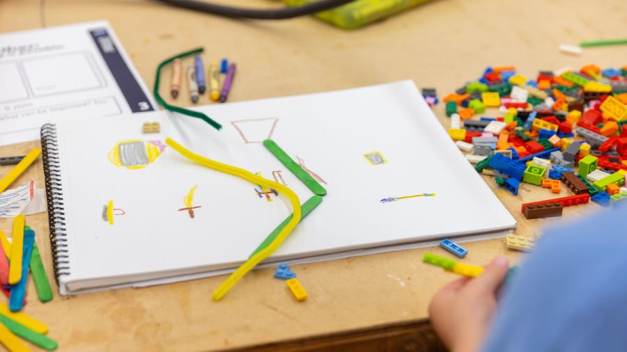 A first-grade student bends pipe cleaners to design a toy sword.