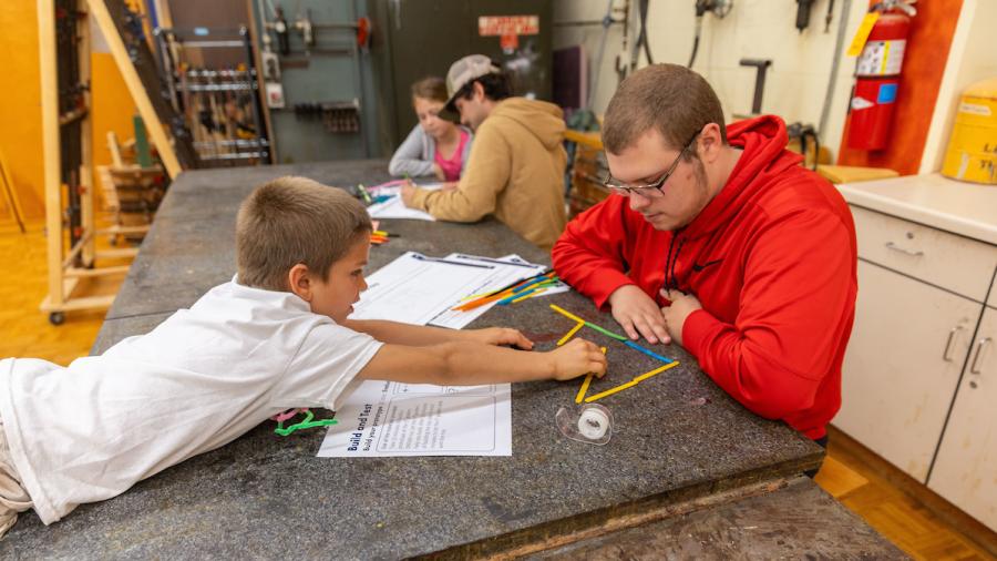A Design for Industry student and first-grader use popsicle sticks to design a toy.
