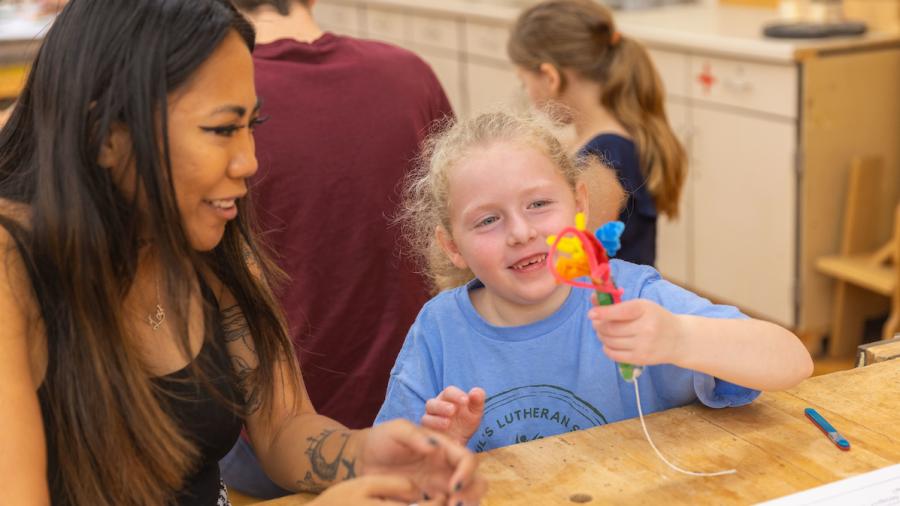 Business administration student Lou Enriquez and a first-grader design toy fireworks with pipe cleaners.