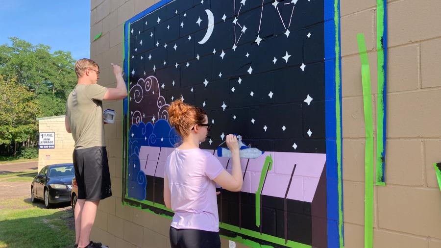 Melanie Graves and a friend paint her 'Dream Big' mural for the Eau Claire Color Block
