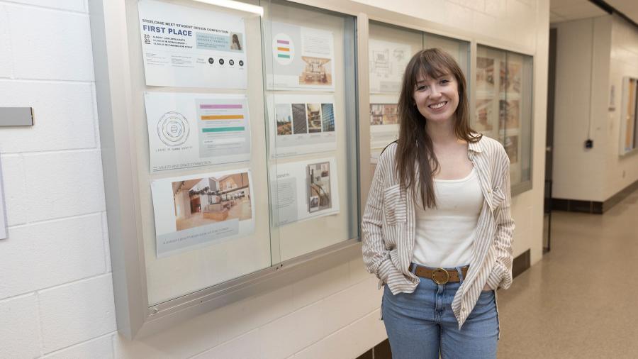 UW-Stout interior design senior Khendra Thompson poses with a display of her winning entry in the Steelcase NEXT Student Design Competition.
