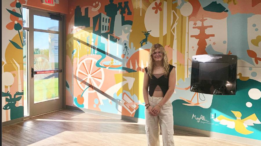 A student stand in front of a mural in a dental office