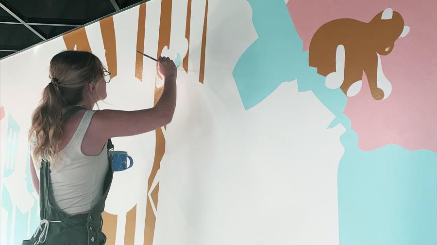 A student paints a mural in a dental office