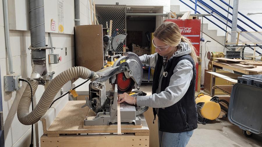 An industrial design student cuts a wooden slat with a table saw in the Process Lab.