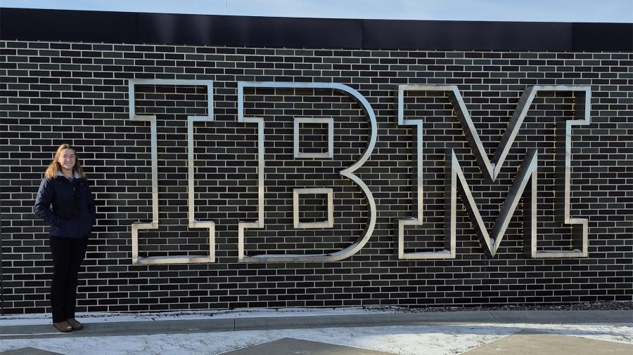Amber Kuhn stands next to the IBM sign at her place of internship