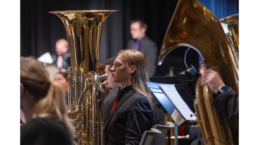 A tuba player in the Symphonic Band, with other band members in the background