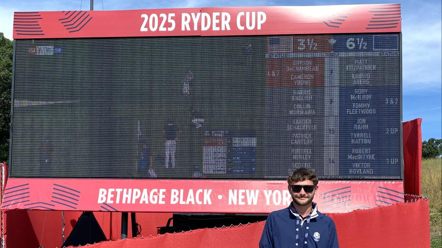 Main in front of golf scoreboard