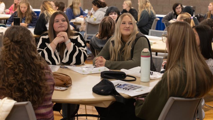 Students sit at a round table and talk at a conference