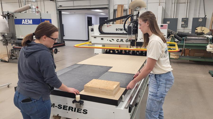 Andrea Smith and Brook Derks ready their ukulele jig for the CNC machine.
