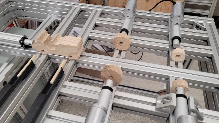 Toy wooden tractor components are lined up with actuators on an assembly line 