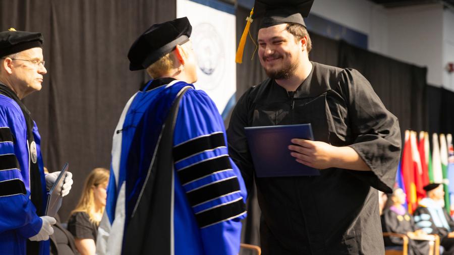 Chancellor and graduate shake hands