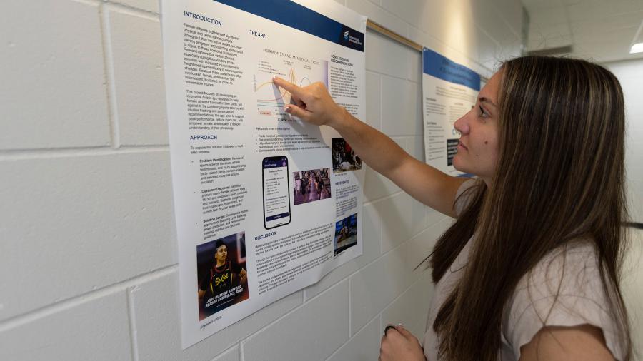 Woman points to research poster