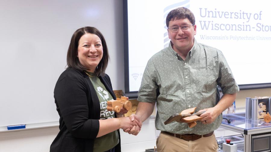 Professor Kevin Dietsche presents Megan Hines with two wooden toy samples
