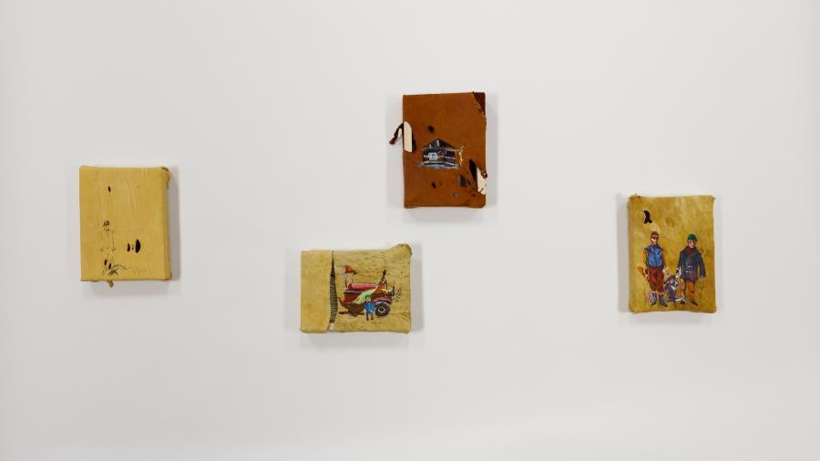 Four small handmade artworks displayed on a white wall in an asymmetrical arrangement.  Each features colorful illustrations including figures and scenes. The pieces have irregular, hand-torn edges and appear to be mixed media works with a folk art aesthetic.