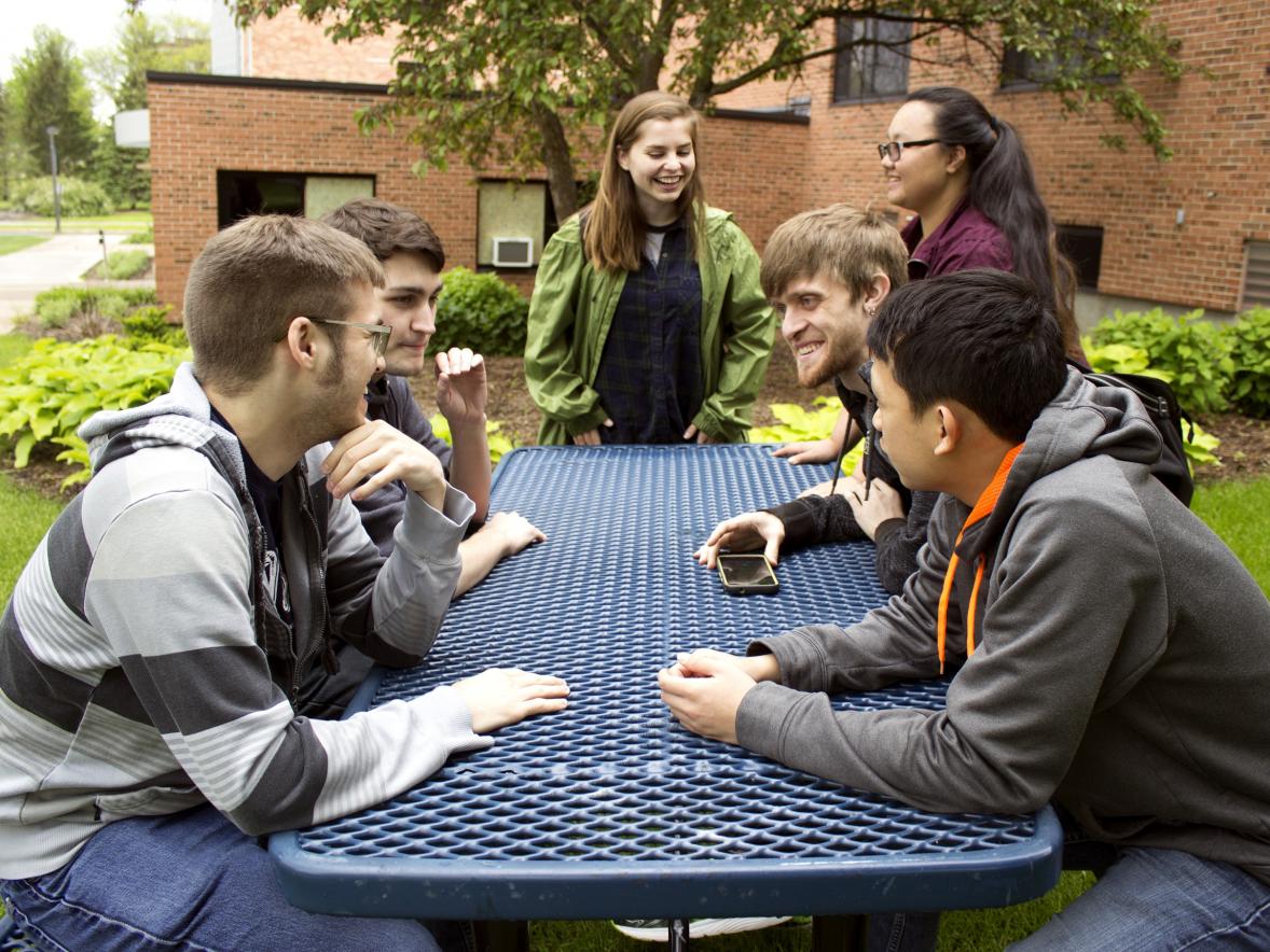 Students outside socializing at a table