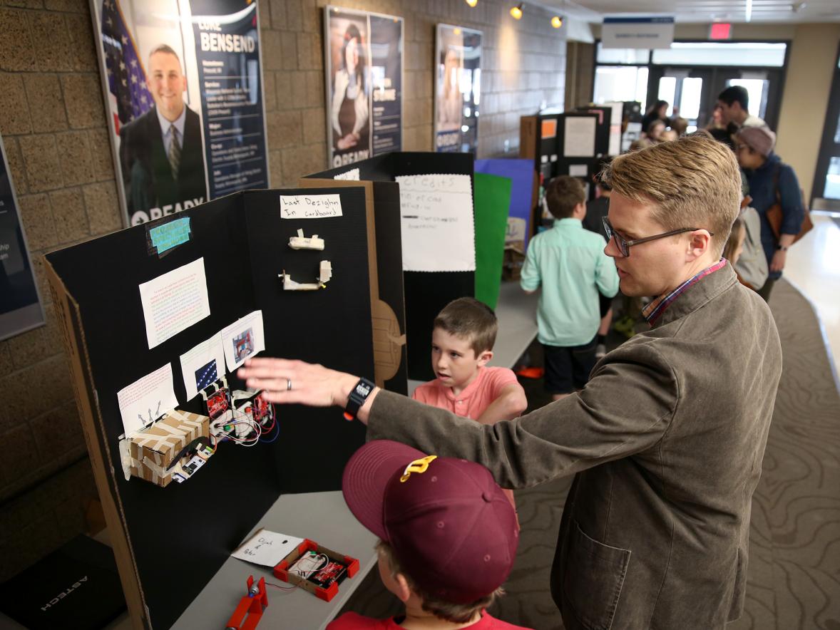 Oaklawn Elementary School students explain their research to Devin Berg, UW-Stout program director for mechanical engineering and an associate professor, during UW-Stout’s Research Day. Twenty two elementary school students shared their research during the event. /UW-Stout photo by Brett T. Roseman.
