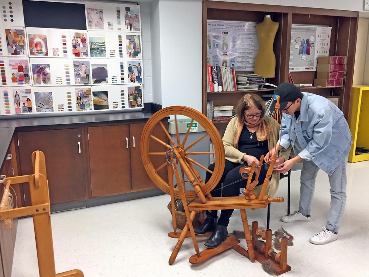 UW-Stout alumna Cindy Boehm shows student Kennedy Lor how to operate a spinning wheel that Boehm donated to the apparel, development and design program. / UW-Stout photos by Pam Powers