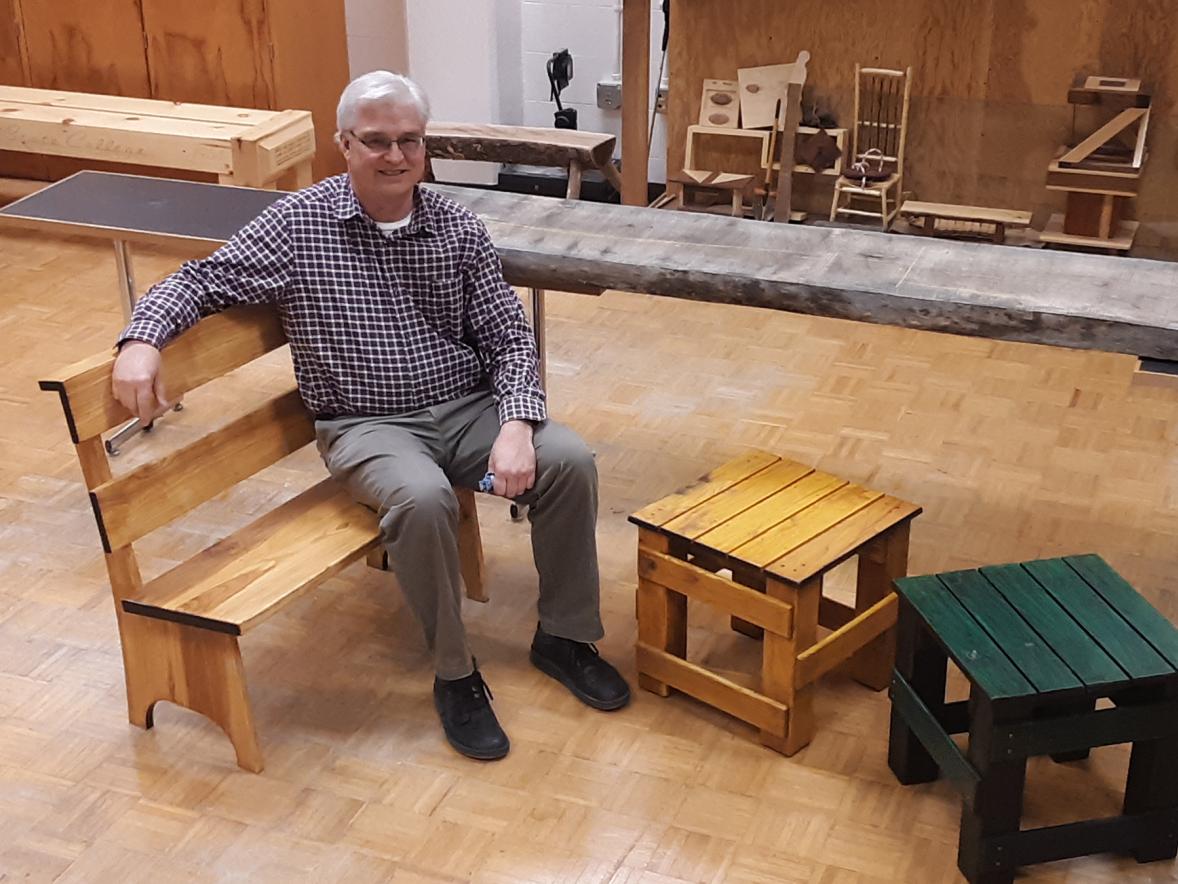 UW-Stout Professor Jerome “Jerry” Johnson sits on one of the benches made by students he has worked with since 2017, as part of a Menomonie Urban Forestry Board project.