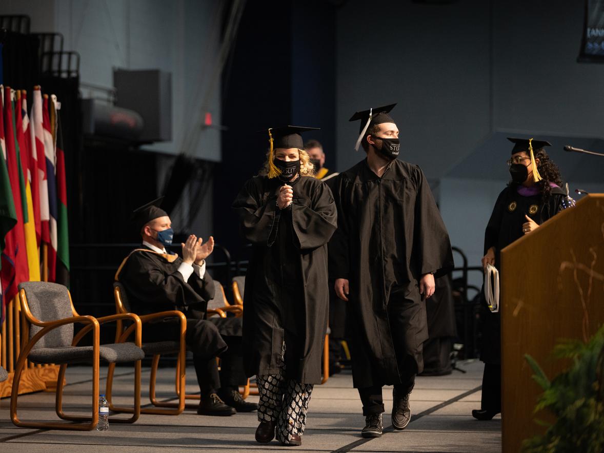 Mara and Jacob Harter walk across the commencement stage