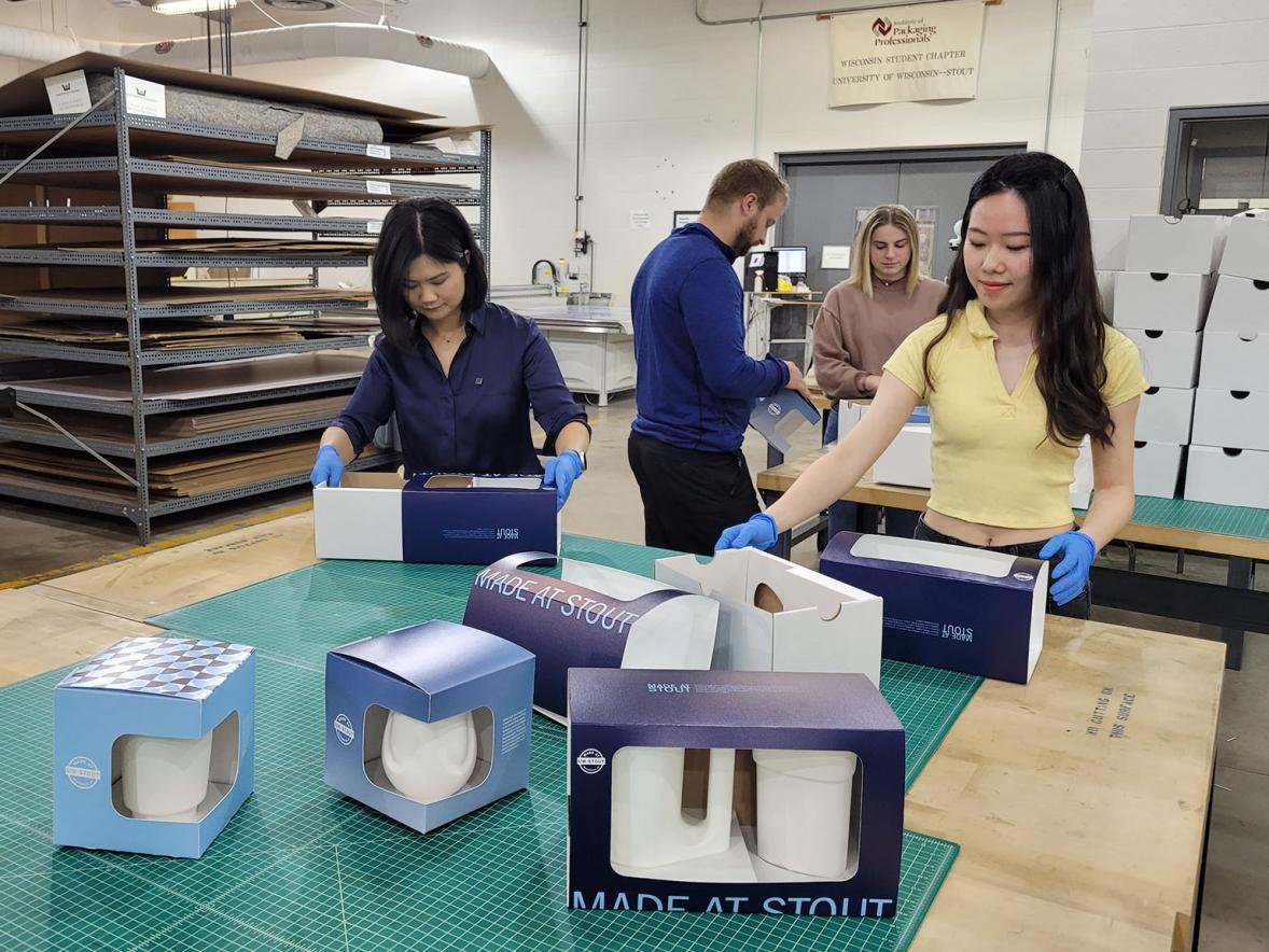 Packaging and graphic design students and faculty package porcelain mugs for the chancellor's investiture.
