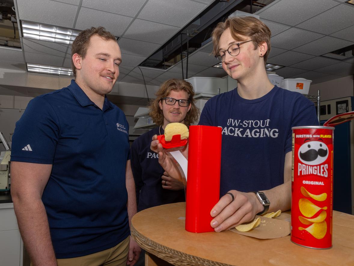 UW-Stout packaging student Ethan Myers, right, demonstrates a feature of the Pringles can that he and teammates Lukas David, left, and Zach Hoffmire designed to win first place in an international competition.