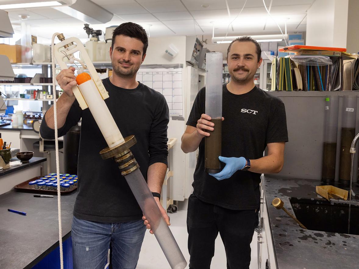 CLRR Field Coordinator Andrew Schneyer, left, and Laboratory Coordinator Conor Dougherty show a gravity coring device like the one used to take sediment cores on Green Lake in Wisconsin. Conor is holding an intact sediment core.
