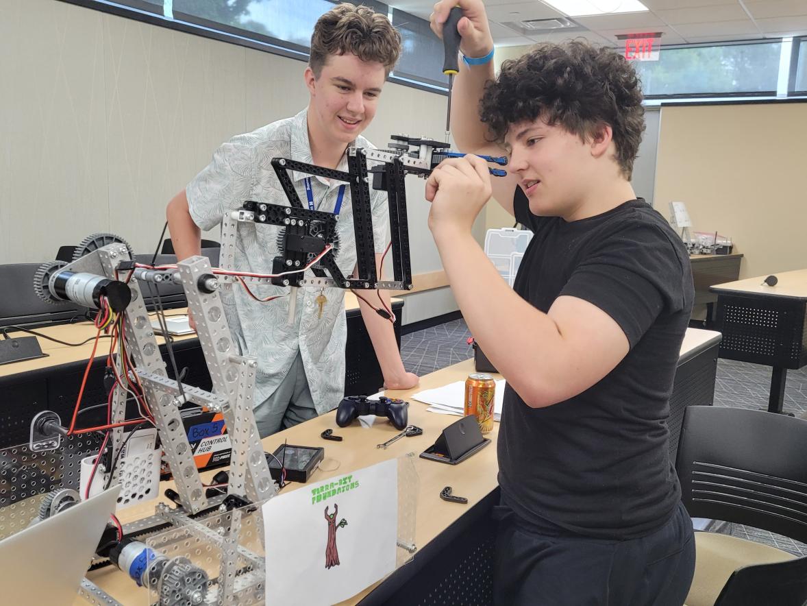 Two students work on a robot they are designing