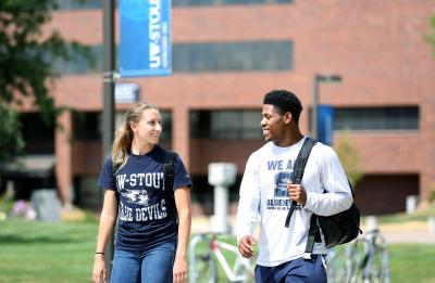Two students conversing as they walk through campus.