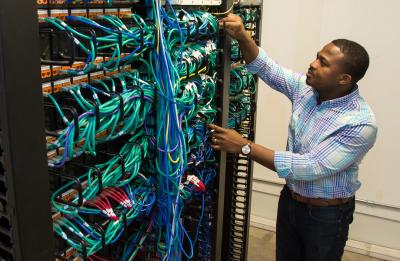 20171208_ms_ict_04.jpg Emmanuel Mbanali in the telecom/network room at the UW-Stout Admin Building.