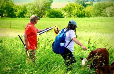 LAKES students Audrey Cho helps farmer Dan Prestebak roll out fencing.
