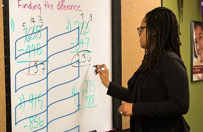 MS Education student writes on board in classroom.