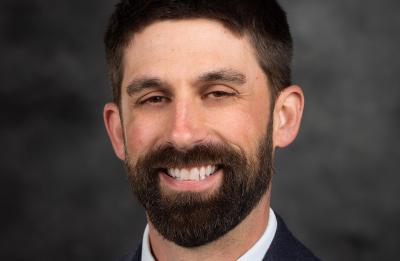 Kevin Masarik is wearing a suit and smiling at the camera.