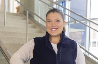 UW‑Stout student ambassador poses on an indoor staircase inside a campus building.