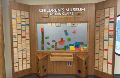 Interactive wall display at the Children’s Museum of Eau Claire featuring colorful magnetic blocks and donor recognition panels surrounding a hands-on activity board.