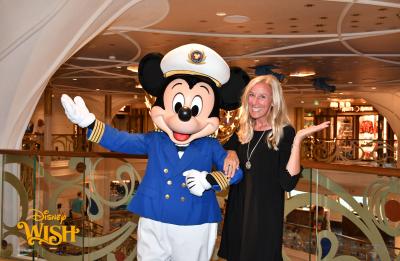 A person poses with Mickey Mouse dressed as a ship captain aboard a Disney cruise ship.