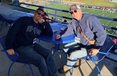 Dave Rasmussen and a family member sit together overlooking a UW-Stout Blue Devils football game.