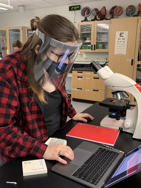 Erin Hongerholt, wearing one of 3,000 face shields donated to UW-Stout by Prent Corp., works at a microscope during her Human Biology course lab in Jarvis Hall Science Wing.