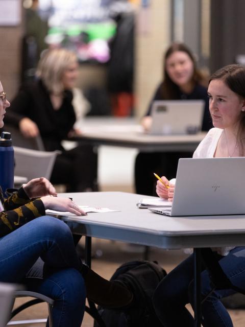 Two students sitting at a table with a laptop