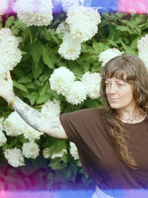 Faythe standing in front of white hydrangeas, extending her arm
