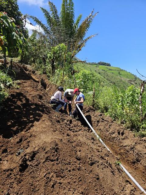 The students and villagers work on the water system pipeline, which is buried on the mountainside and will be about two miles long when finished.