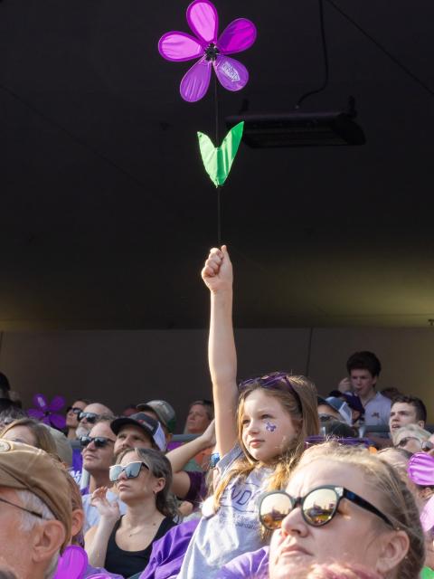 A girl holds a colorful flower at an Alzheimer's disease awareness event