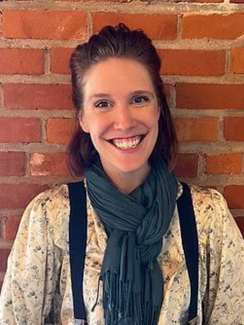 picture of long haired female standing with a brick background