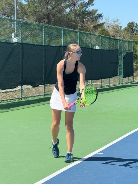 UW-Stout tennis player prepares to serve during a match on an outdoor court at the USTA National Campus.