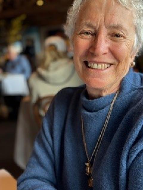 Portrait of a person wearing a blue sweater seated indoors.