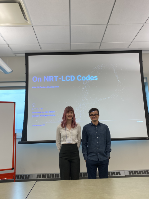 Julia Grimm stands with a colleague in front of a presentation screen displaying research on NRT-LCD codes at a professional conference.